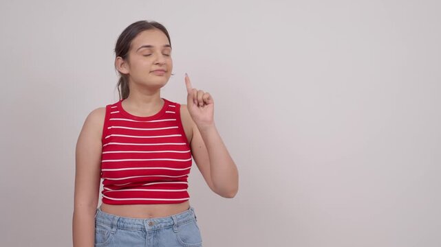 Indian Teenage Girl Pointing at Blank Advertising Space and Showing Thumbs Up