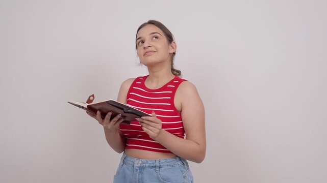 Indian Teenage Girl Reading Notebook and Looking Up Thoughtfully