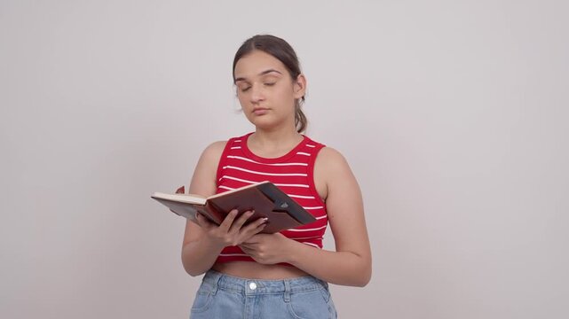 Indian Teenage Girl Reading from Notebook and Looking at Camera