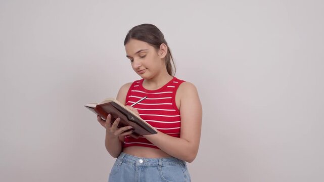 Indian Teenage Girl Writing in Notebook with a Smile