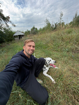 Happy Man Taking Selfie With Dalmatian Dog Outdoors In Countryside Field