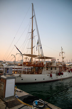 Cannes, France - July 30, 2026: A large classic yacht with a tall mast and wooden decks is docked in a harbor at sunset