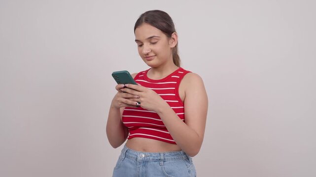 Happy Indian Teenage Girl Texting on Mobile Phone and Smiling