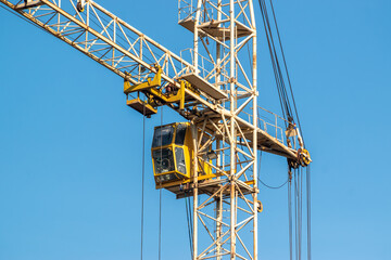 Tower crane cab and boom close up against blue sky © Dmitry