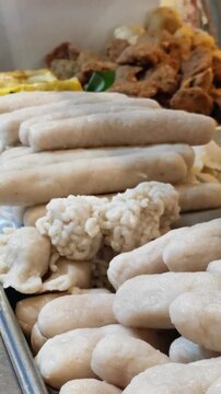 Various shapes of uncooked traditional Indonesian pempek fishcake on display tray