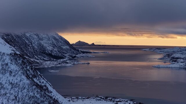 Aerial view of snowy mountains and sea at golden hour sunset, Norway