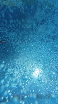 Underwater view of air bubbles and sunlight on swimming pool surface