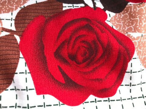 Embroidered red rose pattern on fabric with geometric background lines textile design floral embroidery sewn flower cloth decoration stitch work