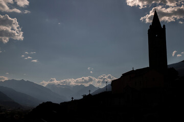 Church silhouette against mountains, dramatic sky, and crosses © Valenti