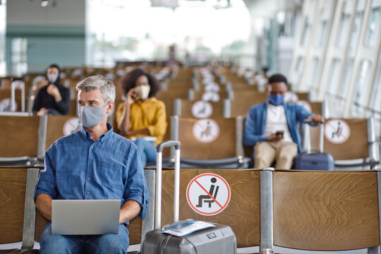 Travelers maintain physical distance in a waiting area with signs indicating seating restrictions during the pandemic
