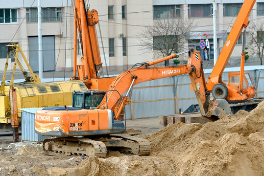 Minsk, Belarus. Jul 15, 2024. Hitachi Zaxis 200LC tracked excavator operating on large sand pile at an urban construction site with heavy machinery, buildings in background. Excavator digging ground