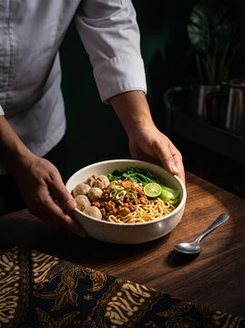 Mie Ayam. Mie Ayam kecap bakmi. Indonesian Chicken Noodle by Chef. Mie Ayam Mangkuk Putih. Chef Holding Classic Indonesian Chicken Noodle in Ceramic Bowl with Dark Moody Atmosphere and Presentation.