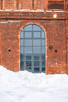Snowy brick facade with arched entrance and festive lights