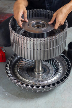 Mechanic installing steel clutch plate into automatic transmission rotating clutch drum assembly.
