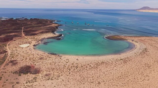 Areal views of Lobos Island, a small, uninhabited volcanic nature reserve with crescent-shaped white sand beach with crystal-clear turquoise waters located in Fuerteventura, Canary Islands, Spain.
