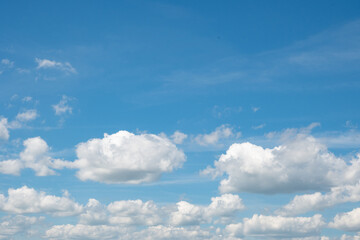 Obraz premium Horizontal bright blue sky featuring large fluffy white cumulus clouds and open clear space. Great for graphic design backgrounds, sky overlays, and summer weather-themed stock imagery.