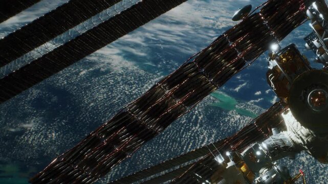 The image shows parts of a space station seen from above. Solar panels extend across the frame. Earth appears in the background, with clouds and land visible below.