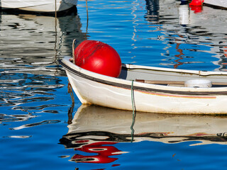 Small Fishing Boats with Bright Red Buoys Reflected in Calm Harbour Waters © susie peek