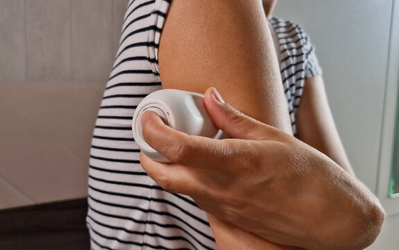 Close-up of a woman applying a continuous glucose monitoring (CGM) sensor to her arm using an applicator for diabetes control