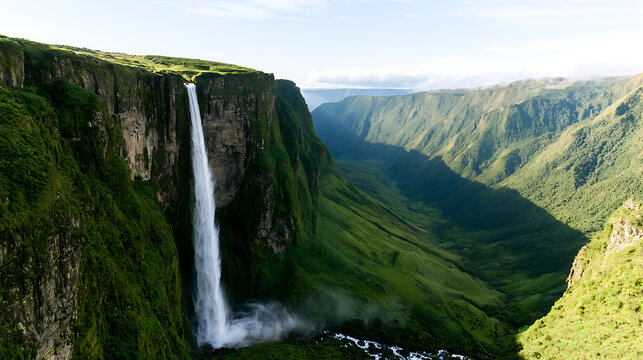 Majestic waterfall cascading down steep green cliff into deep lush valley canyon landscape scenic view nature wilderness adventure travel