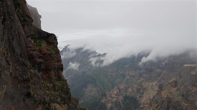Dramatic view of volcanic mountain peaks covered in low clouds and mist on Madeira island, showcasing wild nature and moody atmospheric landscape scenery. 4K video.
