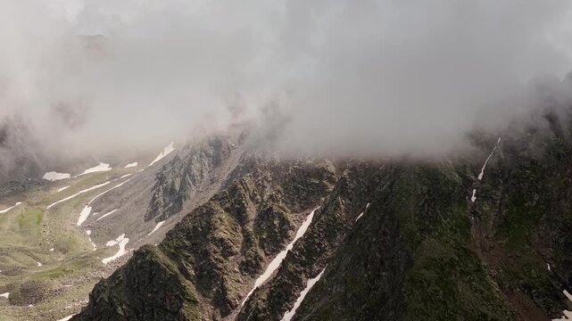 Clouds rolling over high alpine mountain peaks