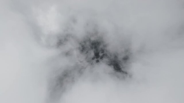Camera descends through dense white clouds revealing green ground