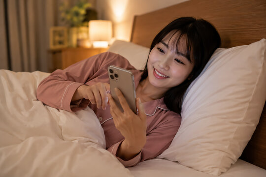スマホに夢中で夜更かしする日本人の若い女性