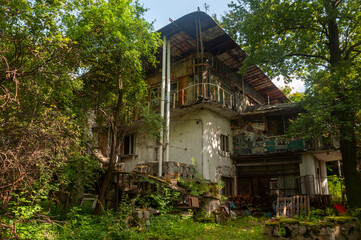 Obraz premium Abandoned overgrown mansion with spiral staircase, old car and ruined interior