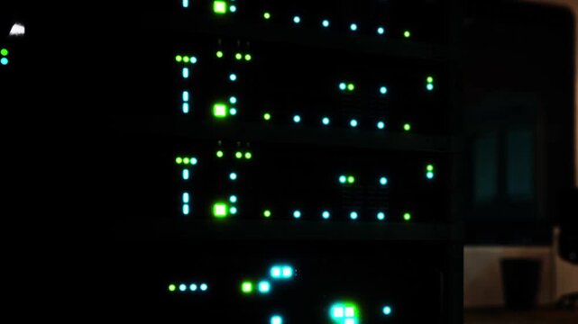 In a data center, lights on multiple servers show activity during evening hours. The setup includes several racks of servers with blinking indicators.