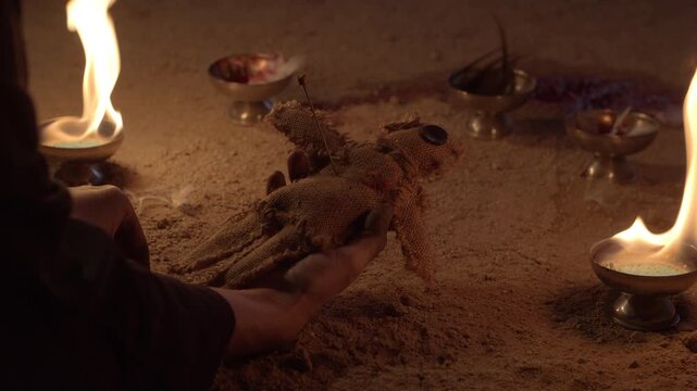 The hands of a woman stab a voodoo doll with a rustic pins in an old black magic ritual