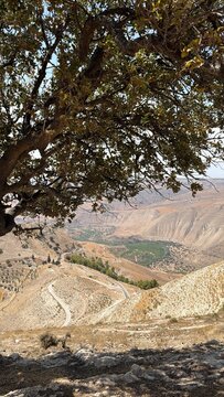A breathtaking high-angle panoramic landscape view overlooking a deep valley and arid mountainous terrain