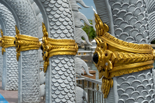 Intricate golden Naga serpent sculptures line a pathway in a tropical setting