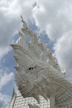 Intricate white Naga serpent sculpture against a cloudy sky