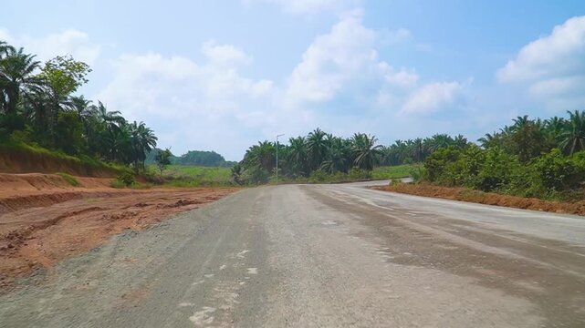 Winding Dirt Highway Construction Site Cutting Through Palm Plantation sawit Forest Red Soil Groundwork Civil Engineering Project Infrastructure Transportation Access Route Regional