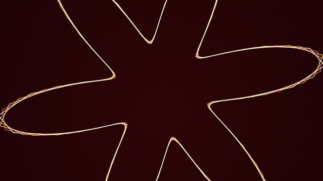 Glowing neon star shapes formed by light painting lines rotating against a deep dark red space