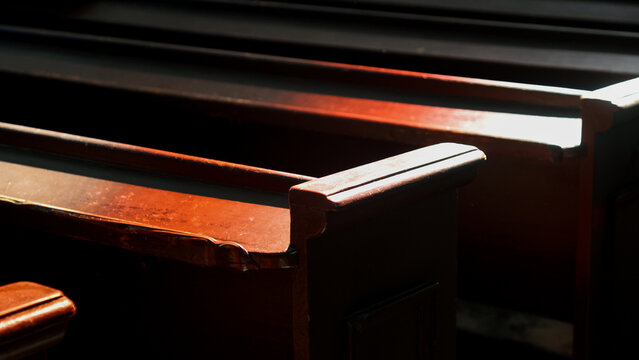 Rows massive wooden pews painted in dark color in old catholic church, wooden benches in cathedral interior, religious background.