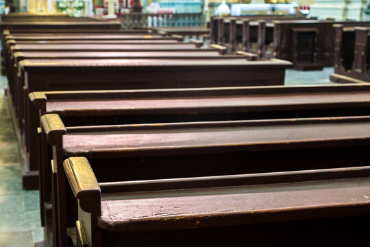 Rows of massive wooden pews painted in dark color old catholic church, wooden benches cathedral interior, religious background.