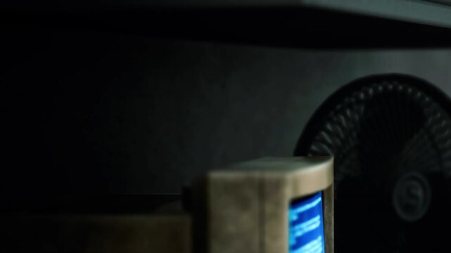 A computer monitor with a blue screen displays an error message. The setting is dimly lit, and shadows from the environment create an eerie atmosphere.