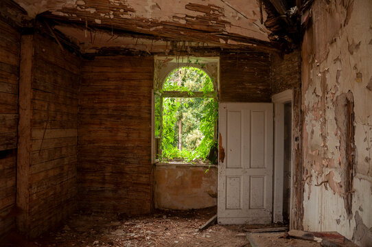 Abandoned overgrown mansion with spiral staircase, old car and ruined interior
