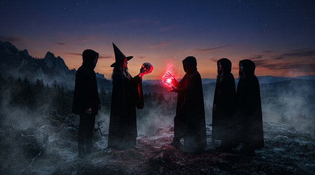 A coven of figures in hooded cloaks and a witch in a hat perform a ritual with a skull and glowing orb at dusk in a foggy, mountainous landscape, symbolizing mystery and magic.