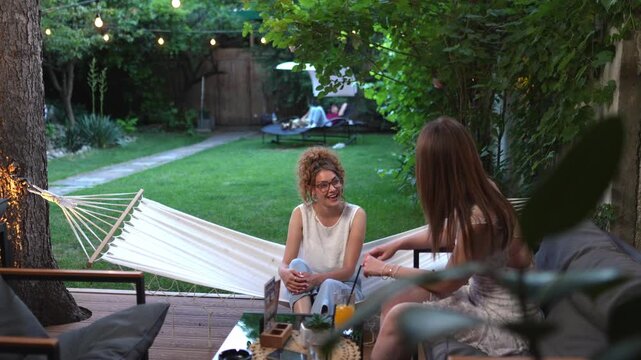 Two young women talking and laughing in a garden cafe