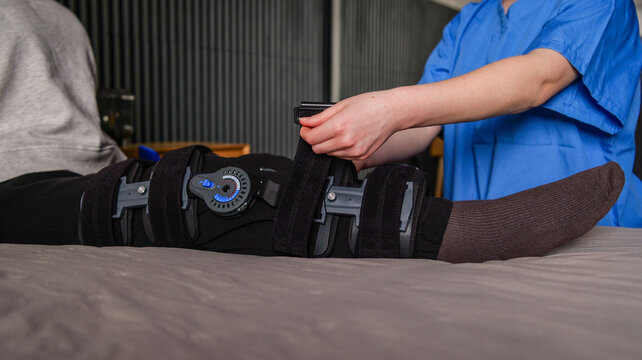 Physical therapist adjusts brace on patient's leg for rehabilitation and recovery