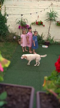 Three sisters playing with dog in backyard