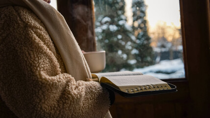 Cozy winter morning with a warm drink and open book by the window
