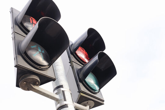 Traffic lights with red vehicle signal and green pedestrian signal against bright white sky. Urban road safety equipment intersection control transport infrastructure and city background.