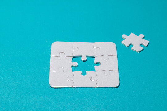 White jigsaw puzzle set with one missing piece in the center isolated on bright cyan background, representing business strategy, solution, and teamwork success. High Quality Photo