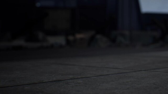 A dark area shows a smooth floor with unclear shapes and objects in the background. The space has a dim light and a quiet atmosphere. There are no visible details or specific items.