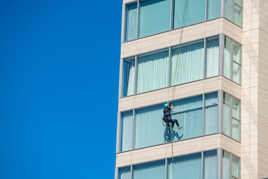 Window cleaner works on high rise building against blue sky, Fukuoka
