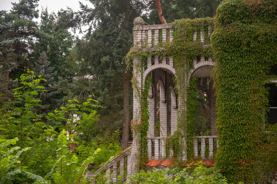 Abandoned overgrown mansion with spiral staircase, old car and ruined interior